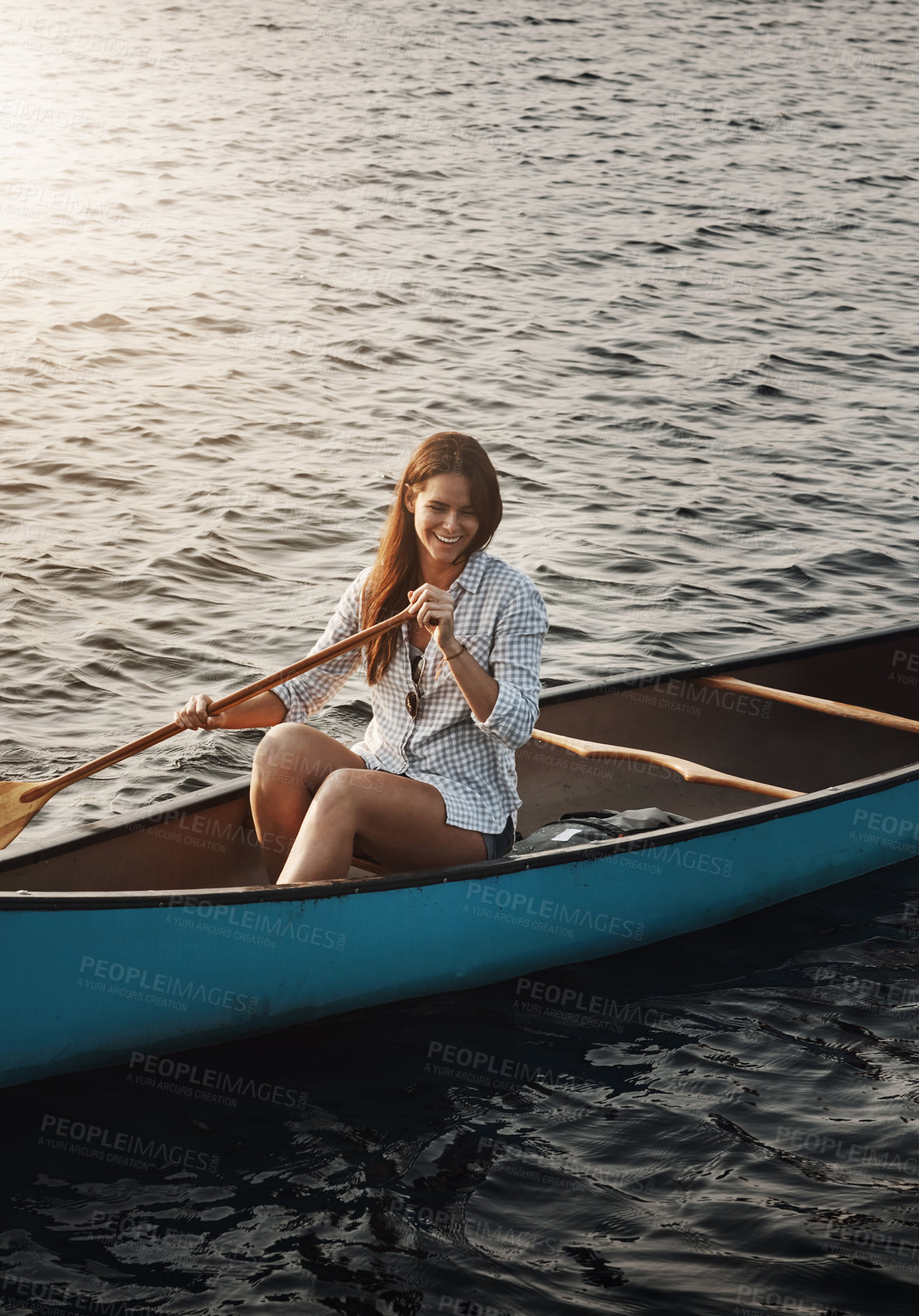 Buy stock photo Shot of a beautiful young woman rowing a boat out on the lake