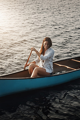 Buy stock photo Shot of a beautiful young woman rowing a boat out on the lake