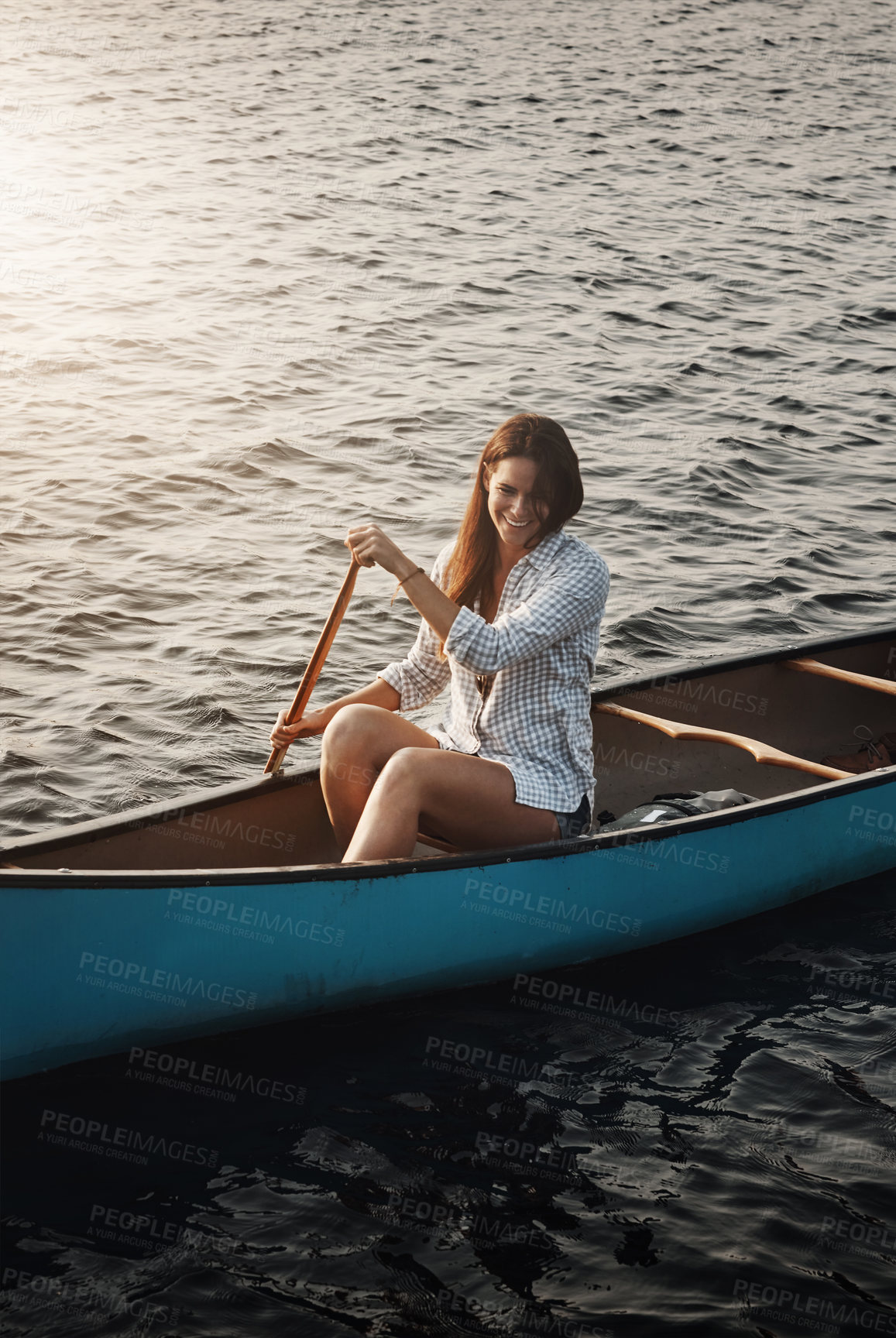 Buy stock photo Shot of a beautiful young woman rowing a boat out on the lake