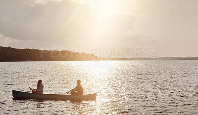 Buy stock photo Shot of a young couple rowing a boat out on the lake