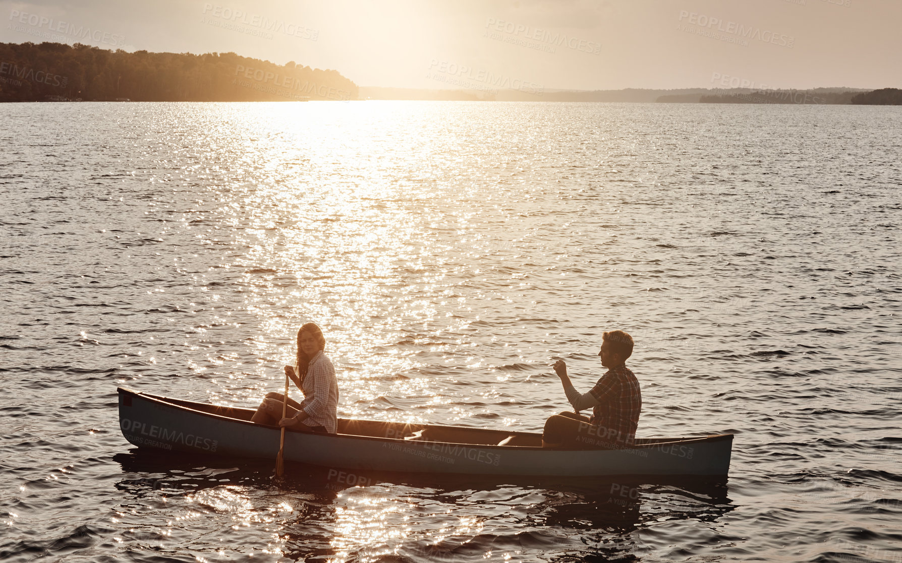 Buy stock photo Shot of a young couple rowing a boat out on the lake