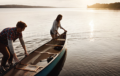 Buy stock photo Nature, travel and couple with boat by lake for adventure, summer and sunset by water. Man, woman and sunshine or happiness for peace, freedom and support for canoe and wellness by river or creek 