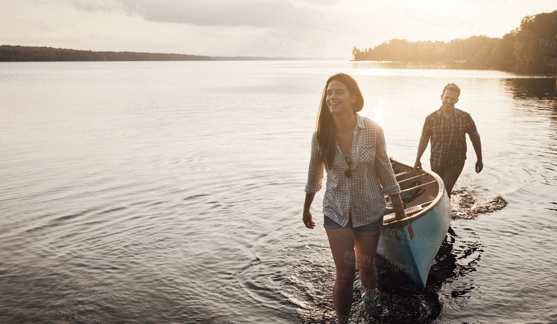 Buy stock photo Happy, journey and couple with canoe by lake for adventure, summer and sunset in nature. Man, woman and sunshine for holiday and travel for freedom, support and boat for wellness by river or water 