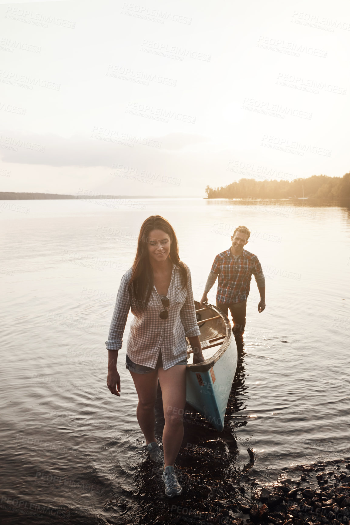 Buy stock photo Shot of a young couple coming from a canoe ride on the lake