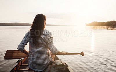 Buy stock photo Rearview shot of a young woman enjoying a canoe ride at the lake