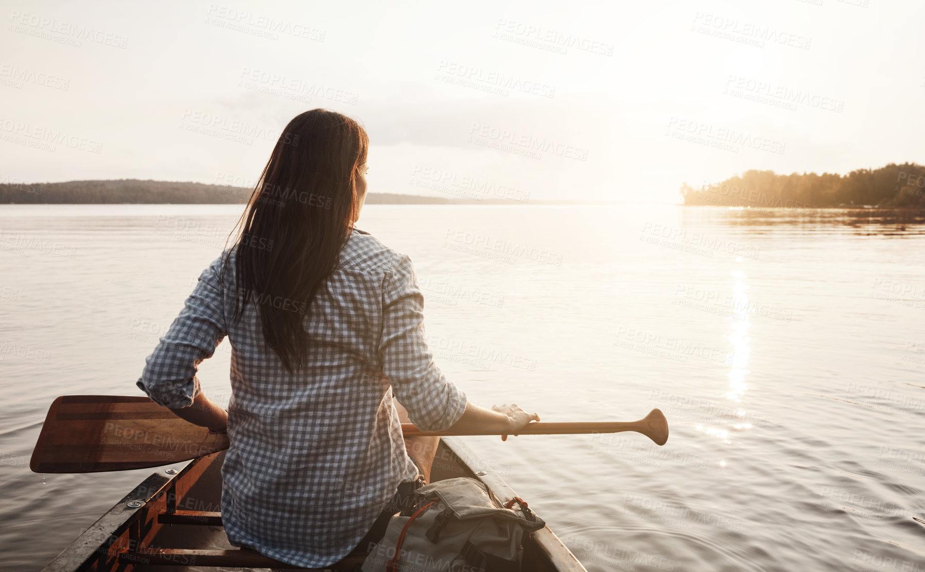 Buy stock photo Rearview shot of a young woman enjoying a canoe ride at the lake