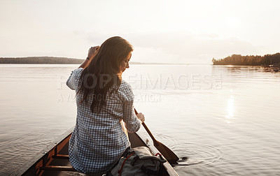 Buy stock photo Rearview shot of a young woman enjoying a canoe ride at the lake