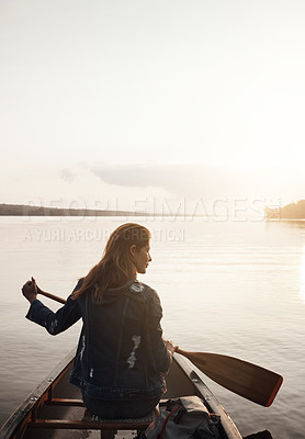 Buy stock photo Rearview shot of a young woman enjoying a canoe ride at the lake