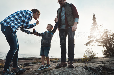 Buy stock photo Shot of a cheerful young family holding hands while taking a quick break from walking outside during the day