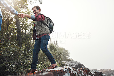 Buy stock photo Shot of a couple crossing over rocks while out exploring nature