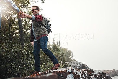 Buy stock photo Shot of a couple crossing over rocks while out exploring nature