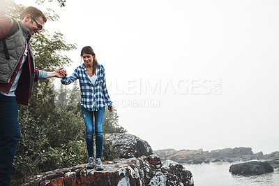 Buy stock photo Shot of a couple crossing over rocks while out exploring nature