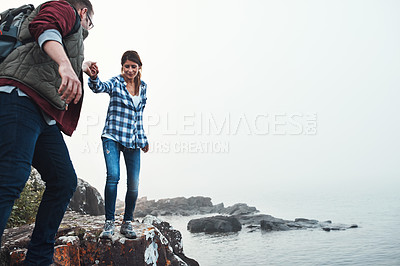 Buy stock photo Shot of a couple crossing over rocks while out exploring nature