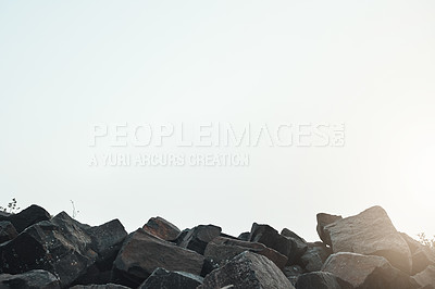 Buy stock photo Shot of a group of sharp rocks next to each with the sun peeking out in the horizon outside during the day