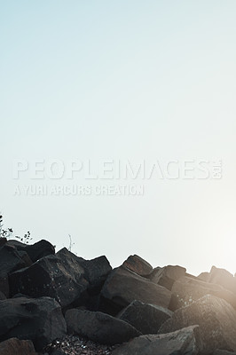 Buy stock photo Shot of a group of sharp rocks next to each with the sun peeking out in the horizon outside during the day