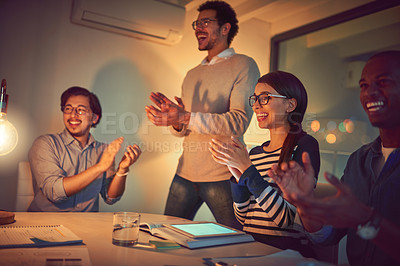 Buy stock photo Shot of a group of designers applauding while working late in an office