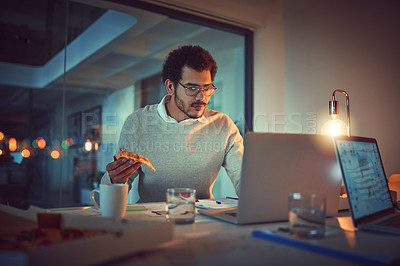 Buy stock photo Shot of a young designer eating pizza while working late in an office