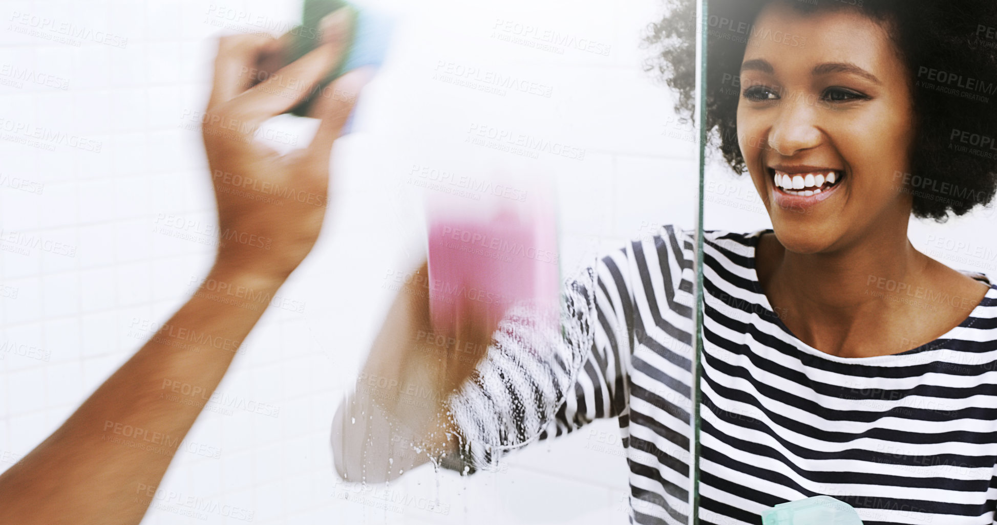 Buy stock photo Shot of a cheerful young woman washing a glass shower door with a sponge in the bathroom at home