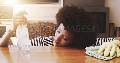 Buy stock photo Shot of a tired young woman resting her head on a table after trying to clean it with cleaning equipment at home during the day