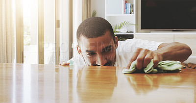 Buy stock photo Shot of a focused young man cleaning the surface of a table with cleaning equipment at home during the day