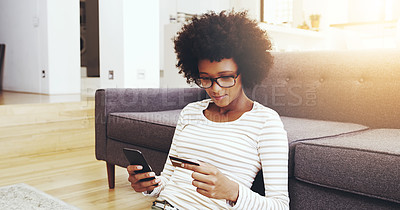 Buy stock photo Shot of a focused young woman seated on the floor while doing online shopping on her computer in the living room at home