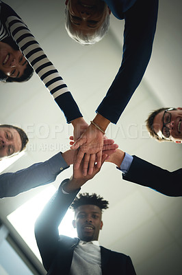Buy stock photo Low angle shot of a group of businesspeople joining their hands together in a huddle