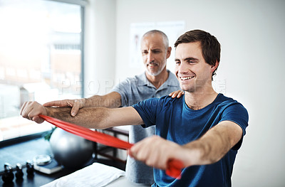 Buy stock photo Shot of a physiotherapist helping a patient stretch with resistance bands