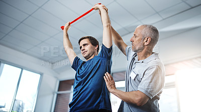 Buy stock photo Shot of a physiotherapist helping a patient stretch with resistance bands