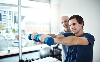 Buy stock photo Shot of a physiotherapist helping a patient work through his recovery with weights