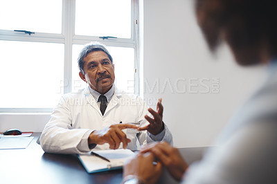 Buy stock photo Shot of a mature doctor having a consultation with a patient in his office