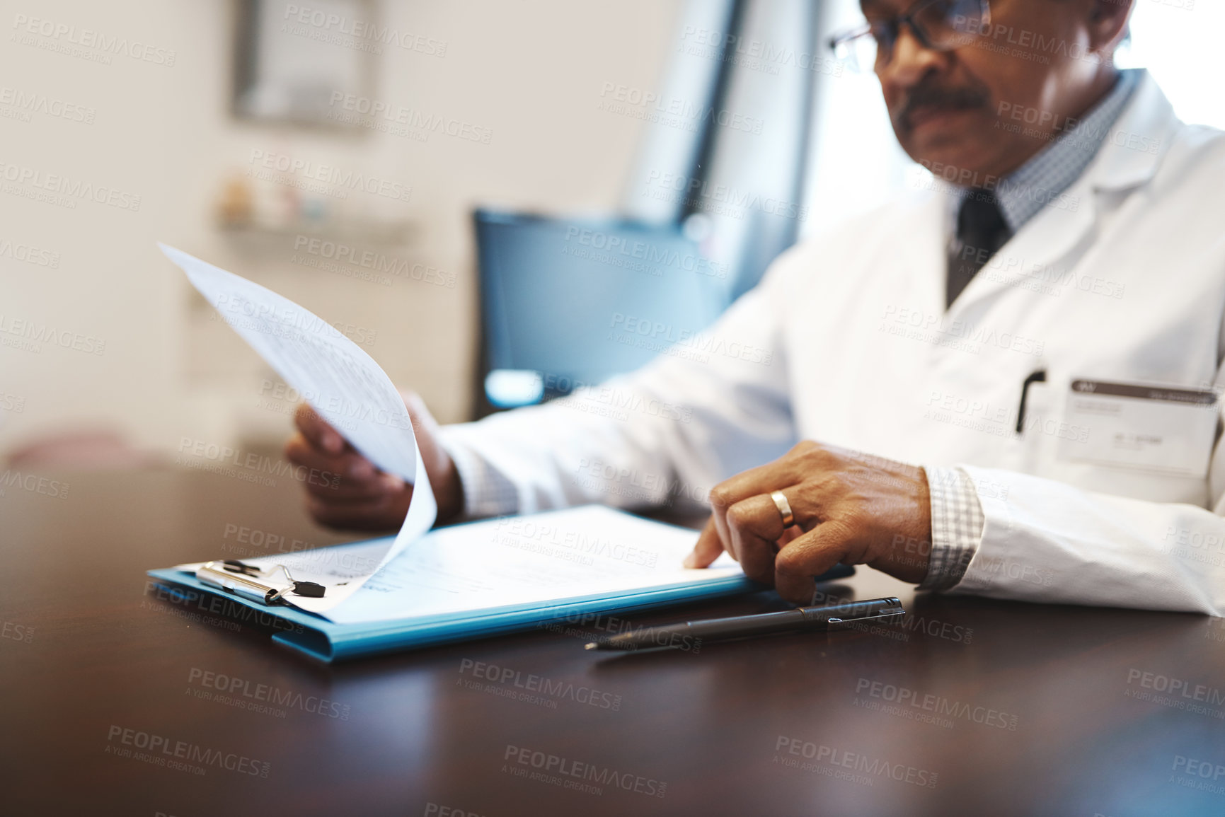 Buy stock photo Shot of a mature doctor going through paperwork in his office