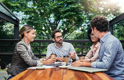Buy stock photo Cropped shot of a group of business colleagues having a meeting outdoors at a cafe