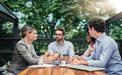 Buy stock photo Cropped shot of a group of business colleagues having a meeting outdoors at a cafe