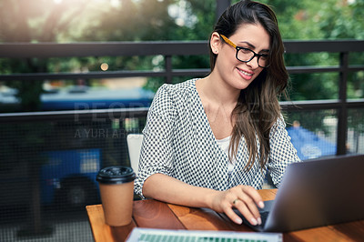 Buy stock photo Cropped shot of an attractive young businesswoman working on her laptop while sitting outdoors at a cafe
