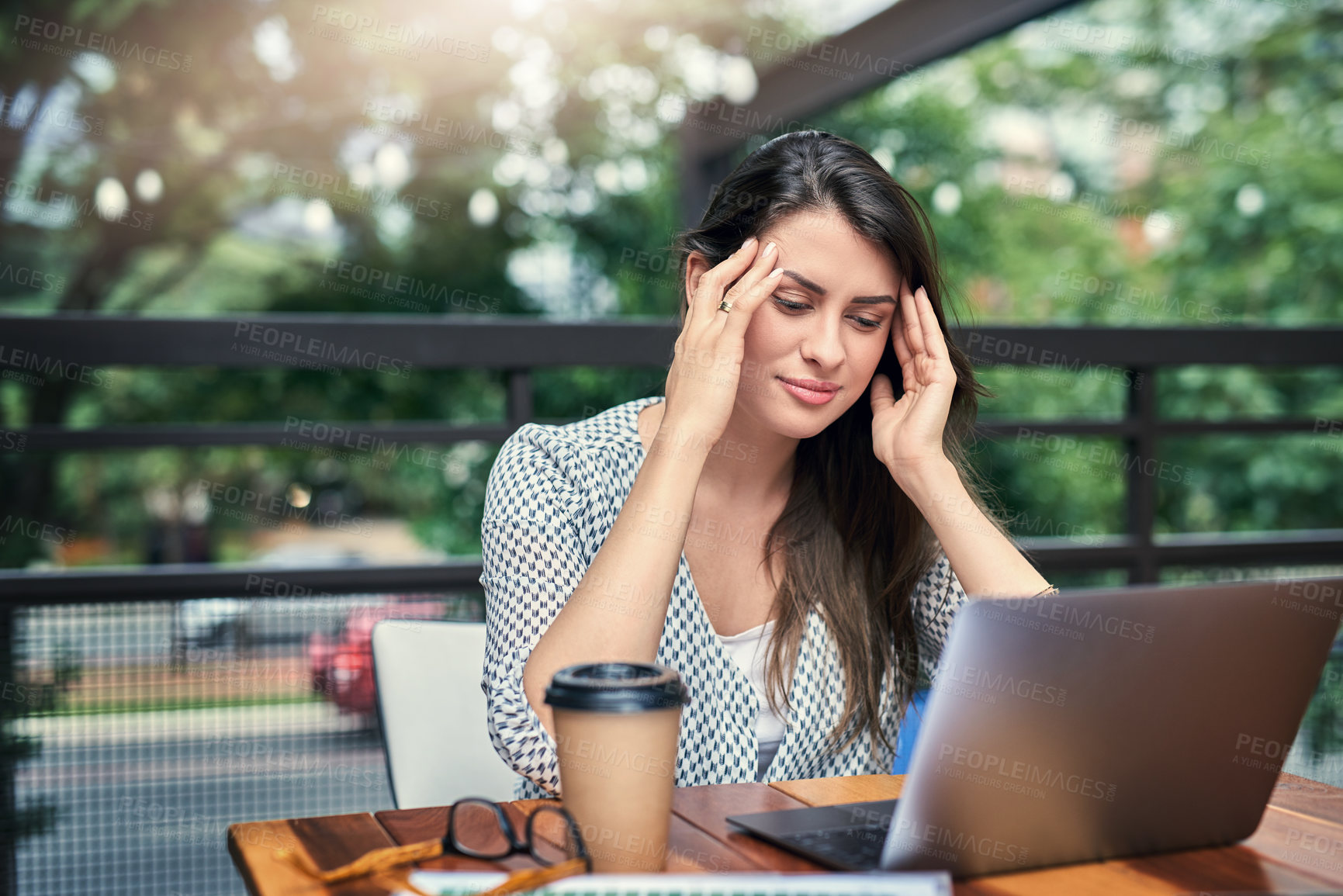 Buy stock photo Cropped shot of an attractive young businesswoman looking stressed while working on her laptop at a cafe