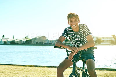 Buy stock photo Cropped portrait of a young boy riding his bike alongside a lagoon