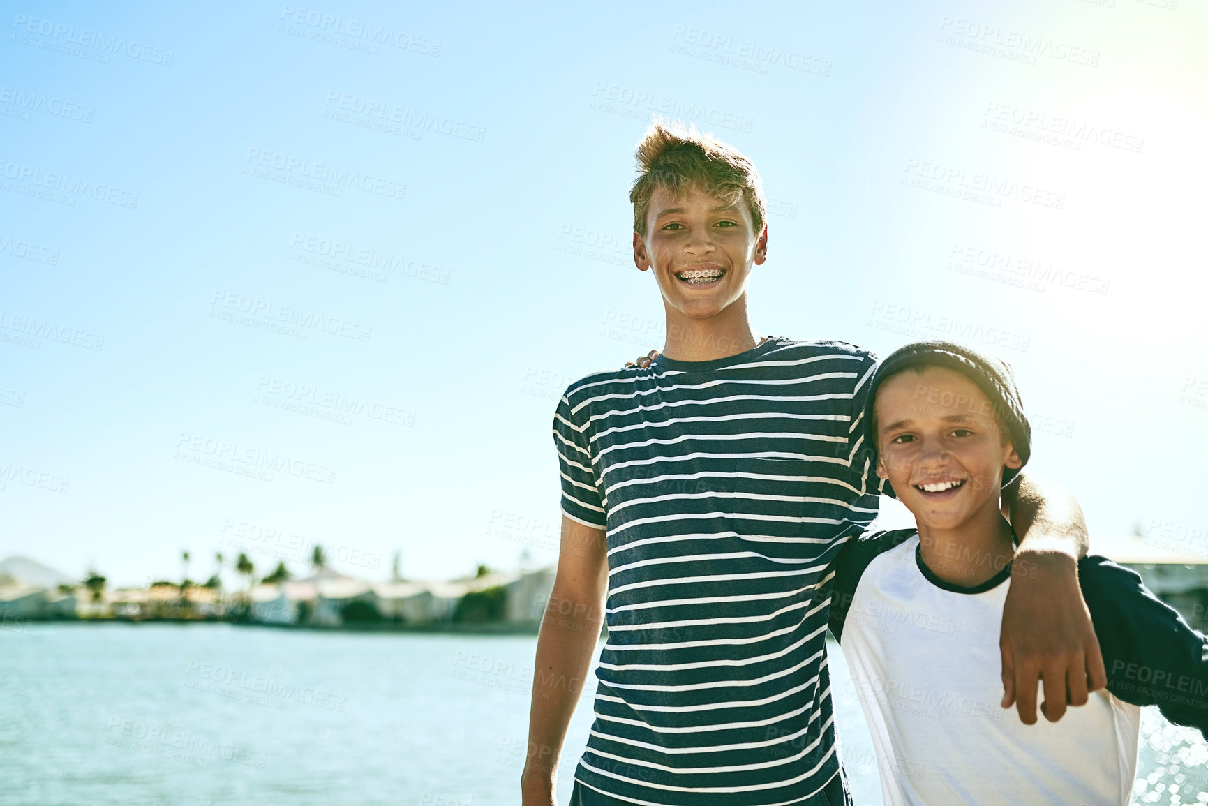Buy stock photo Cropped portrait of two young brothers standing outside with a lagoon in the background