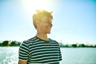 Buy stock photo Cropped shot of a young boy standing outside with a lagoon in the background