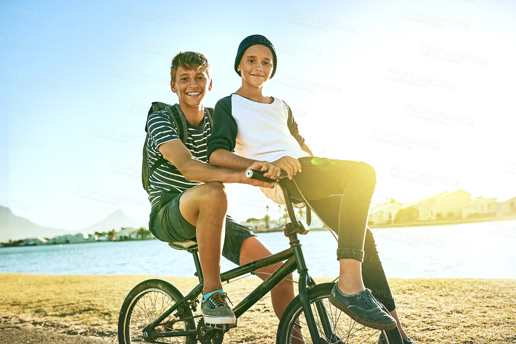 Buy stock photo Cropped portrait of a young boy giving his younger brother a lift on a bicycle outside