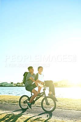 Buy stock photo Full length shot of a young boy giving his younger brother a lift on a bicycle outside