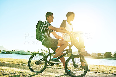 Buy stock photo Full length shot of a young boy giving his younger brother a lift on a bicycle outside
