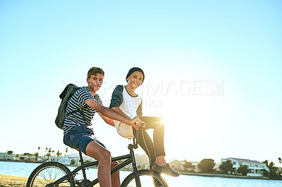 Buy stock photo Cropped portrait of a young boy giving his younger brother a lift on a bicycle outside