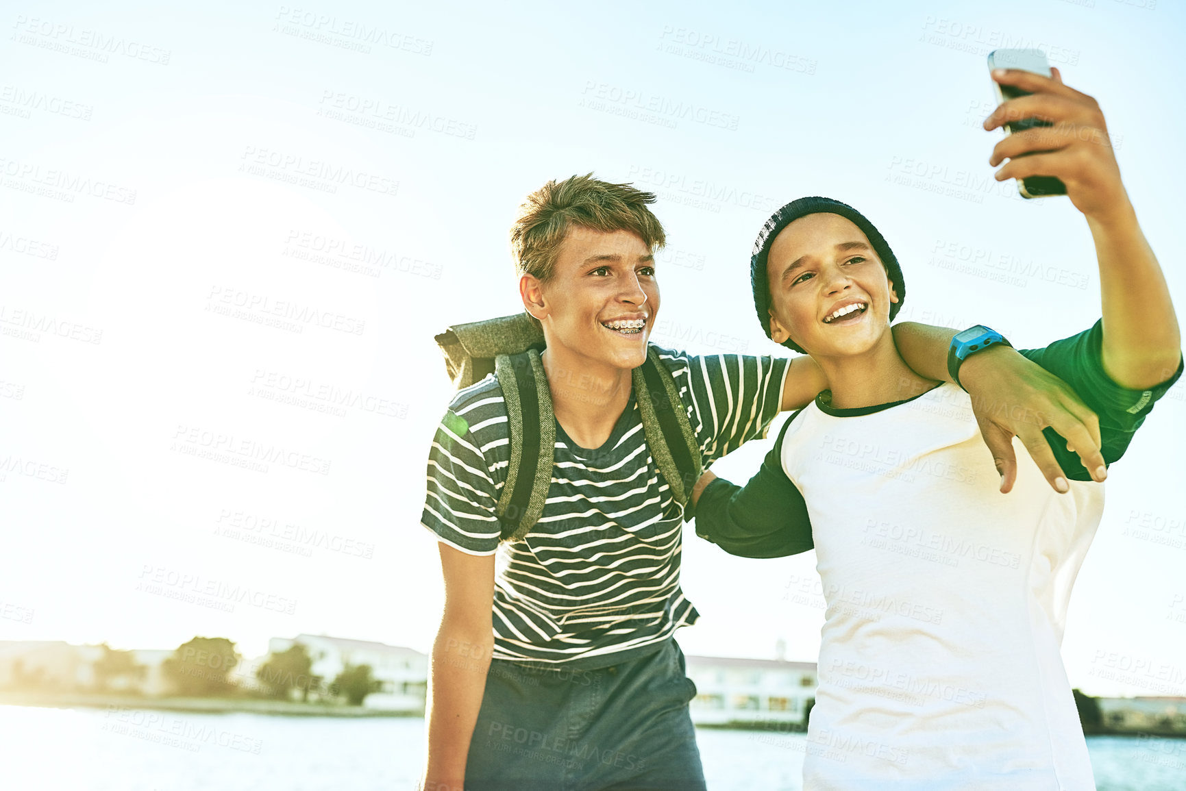 Buy stock photo Cropped shot of two young brothers taking selfies outside with a lagoon in the background