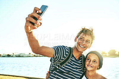 Buy stock photo Cropped shot of two young brothers taking selfies outside with a lagoon in the background
