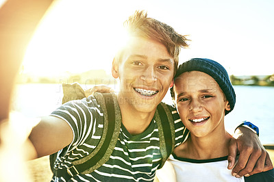 Buy stock photo Cropped portrait of two young brothers taking selfies outside with a lagoon in the background