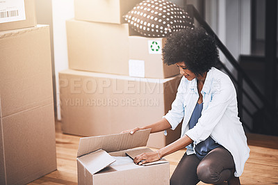 Buy stock photo Cropped shot of an attractive young woman unpacking boxes in her new home