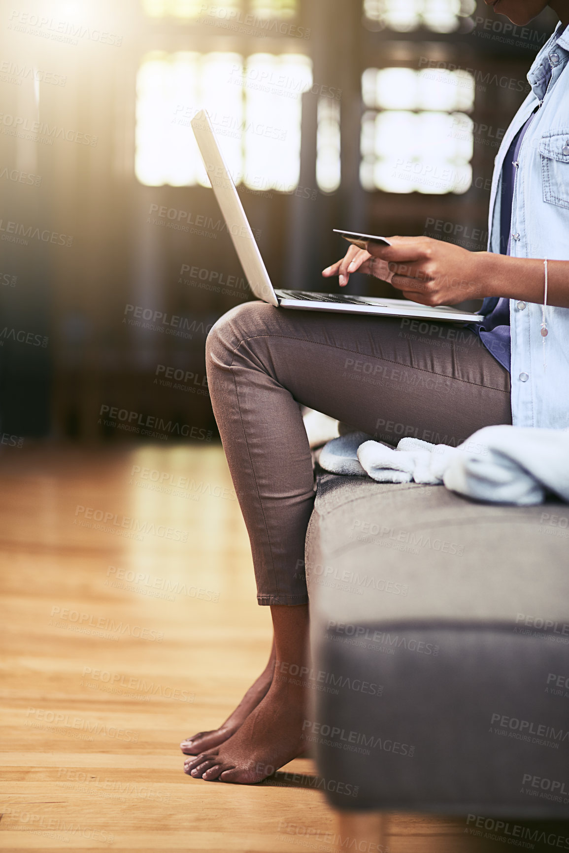 Buy stock photo Cropped shot of a woman using a laptop and credit card on the sofa at home