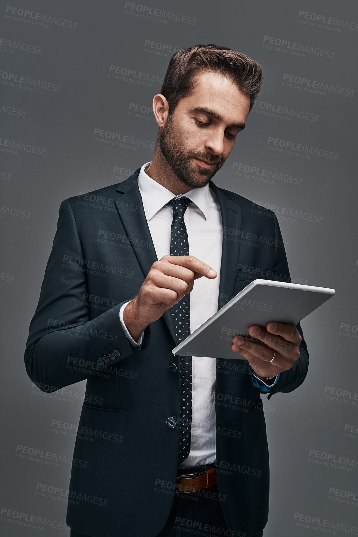 Buy stock photo Studio shot of a handsome young businessman using a digital tablet against a grey background