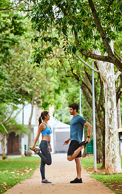 Buy stock photo Shot of a sporty young couple stretching while exercising together outdoors
