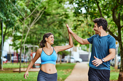 Buy stock photo Shot of a sporty young couple high fiving while exercising outdoors